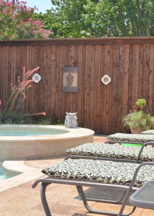 Clôture en bois sur mesure entourant une cour avec une piscine, chaises longues décoratives et éléments de paysage, illustrant l'esthétique et la sécurité pour les espaces extérieurs.