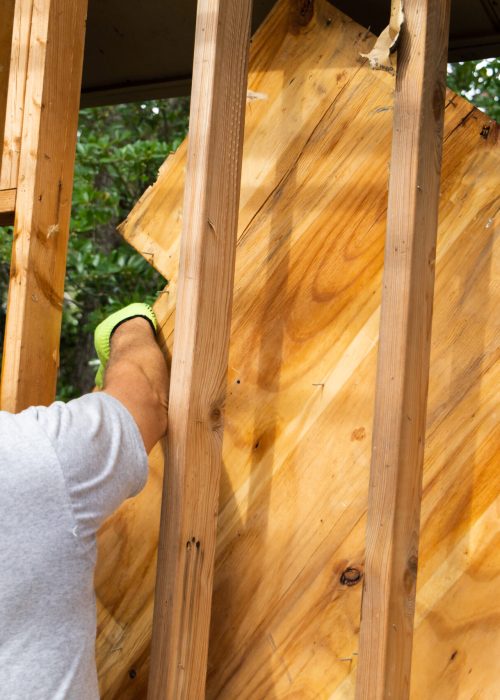 Homme en train de démolir un patio en bois, mettant en avant l'expertise de Patio Exotic dans les services de démolition.