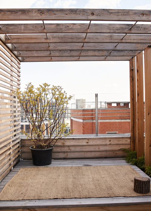 Terrasse en bois avec pergola, pot de plante verte, vue sur la ville, ambiance extérieure accueillante pour projets de patios et aménagements.